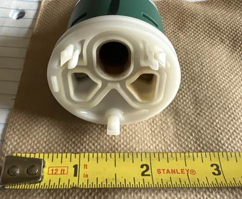 Back end of a shower valve cartridge next to a tape measure