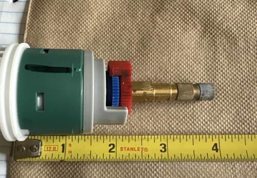 Shower valve cartridge side profile next to a tape measure