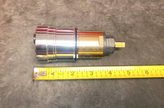 Thermostatic cartridge pieces beside a tape measure showing overall length